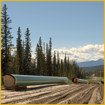 Large green pipes on dirt road near forested mountains