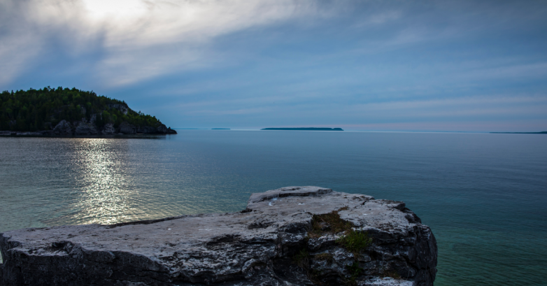 Rocky cliff overlooking calm lake at sunset
