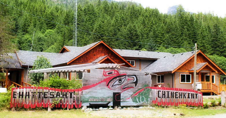 Wooden homes and Indigenous welcome sign in forest