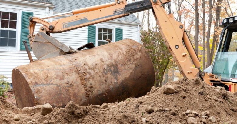 Excavator removing large rusty underground oil tank