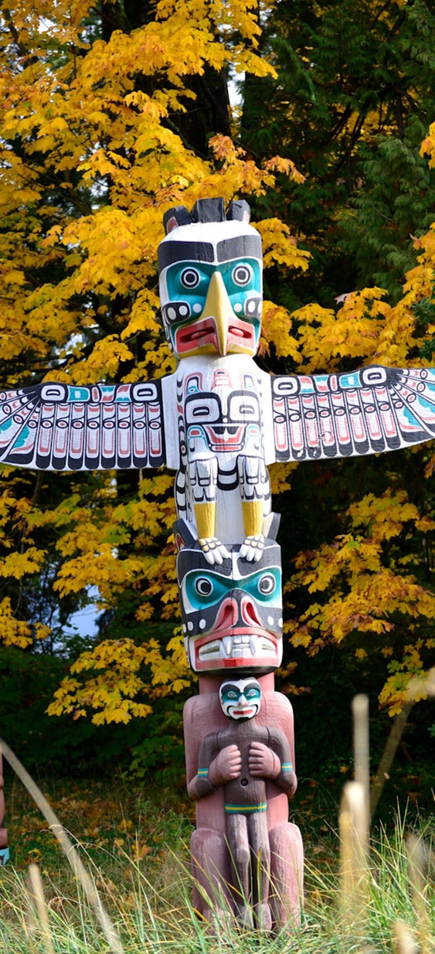 Colorful totem pole with eagle in autumn forest