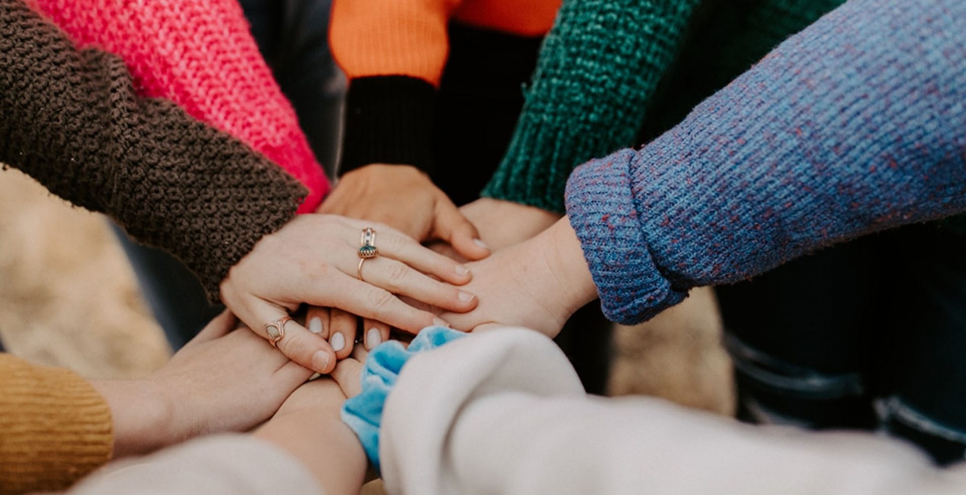 Group of people stacking hands in team huddle