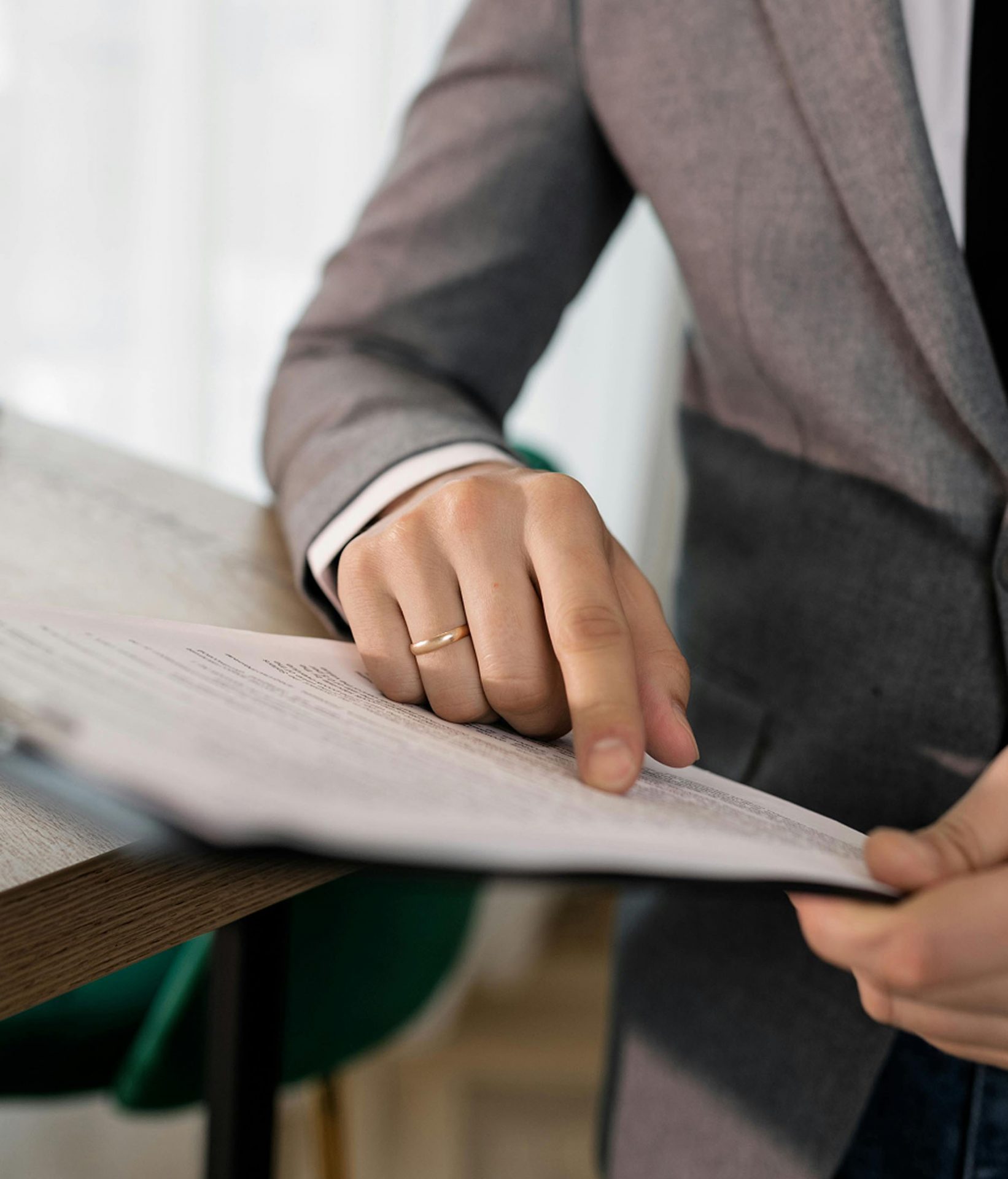 Person in suit pointing at document on desk